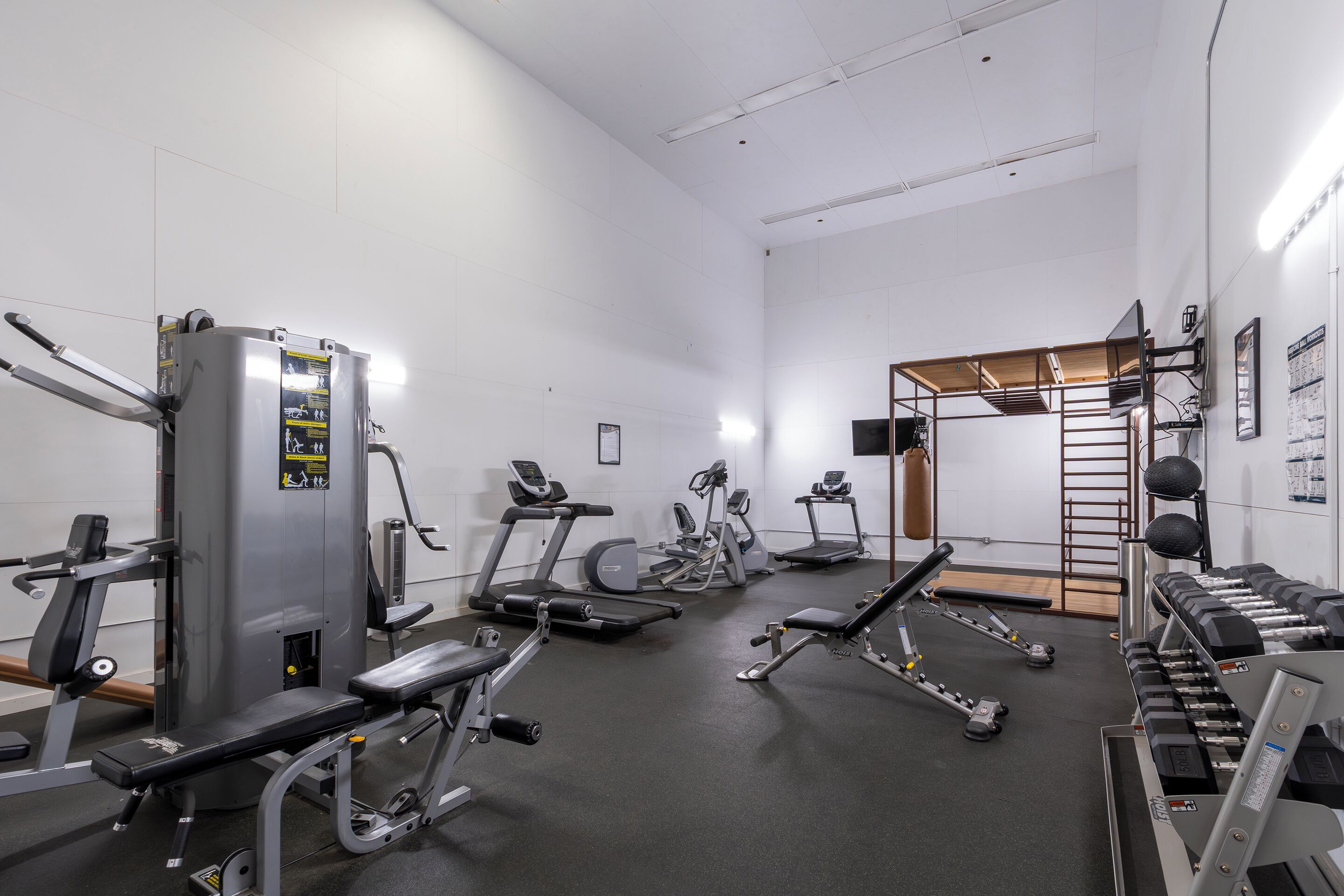 A gym with various exercise equipment including treadmills, weight machines, and dumbbells.