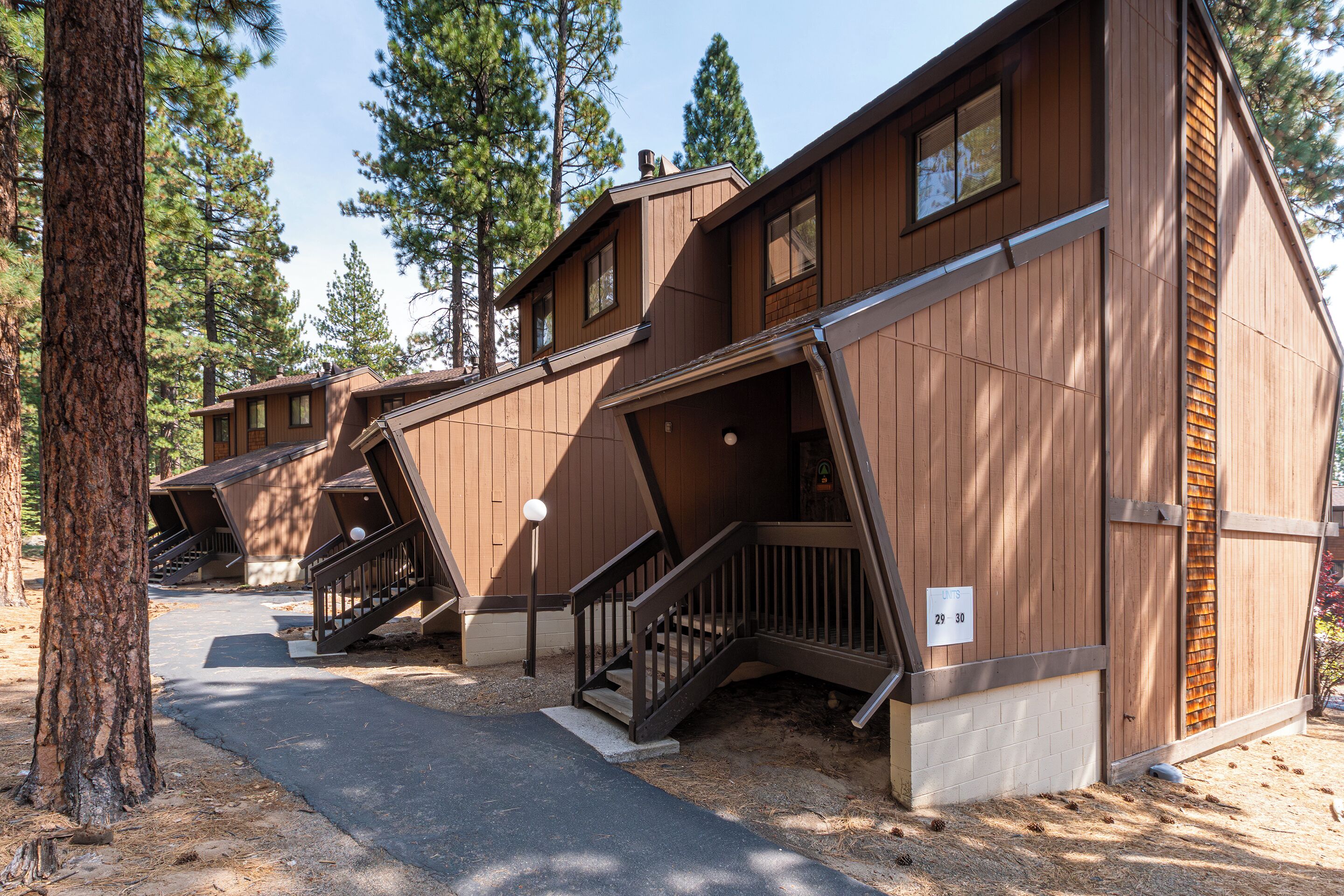 A row of cabins with external staircases, surrounded by trees.