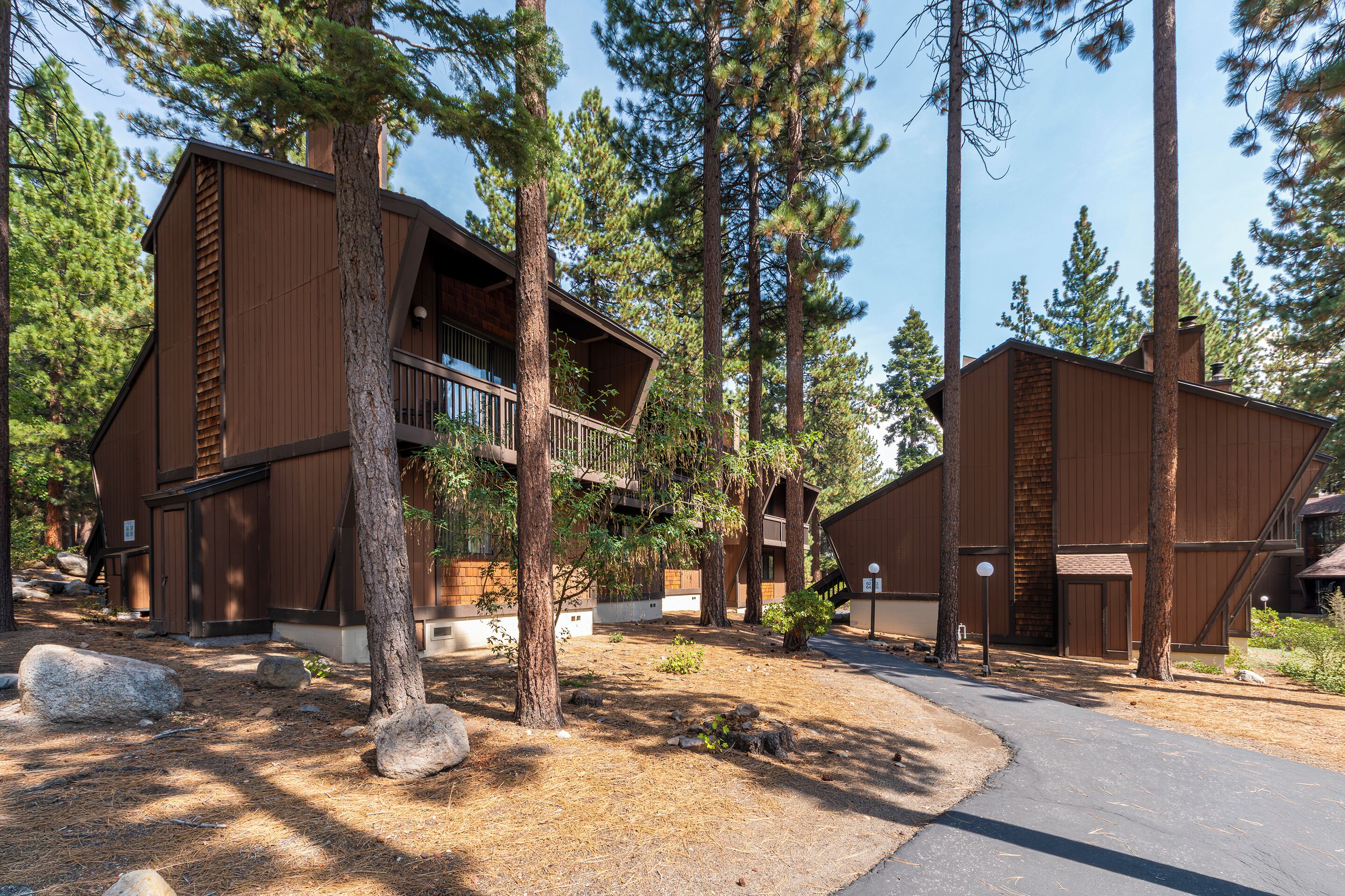Eine Lodge mit Holzfassade, einem Balkon und einem Kiesweg.