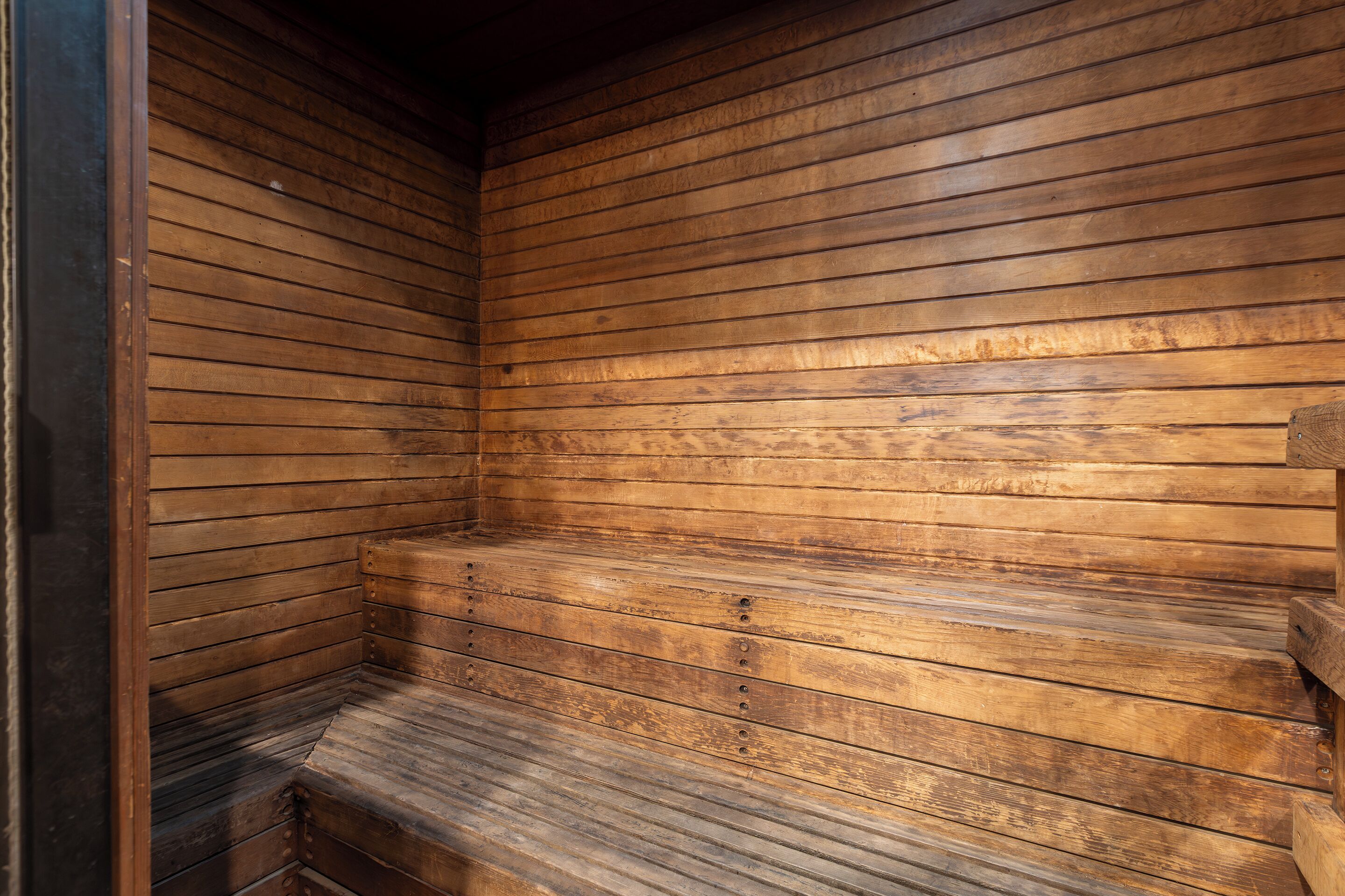 Un sauna en bois, doté de bancs et d’un plafond incliné.