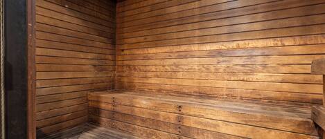Un sauna en bois, doté de bancs et d’un plafond incliné.