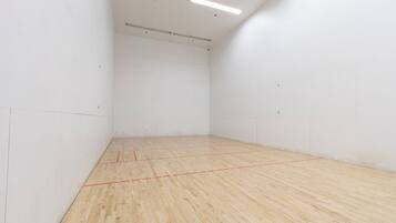 A spacious indoor squash court with a wooden floor and white walls.