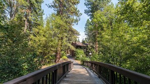Un pont en bois menant à un chalet entouré d’une forêt dense.