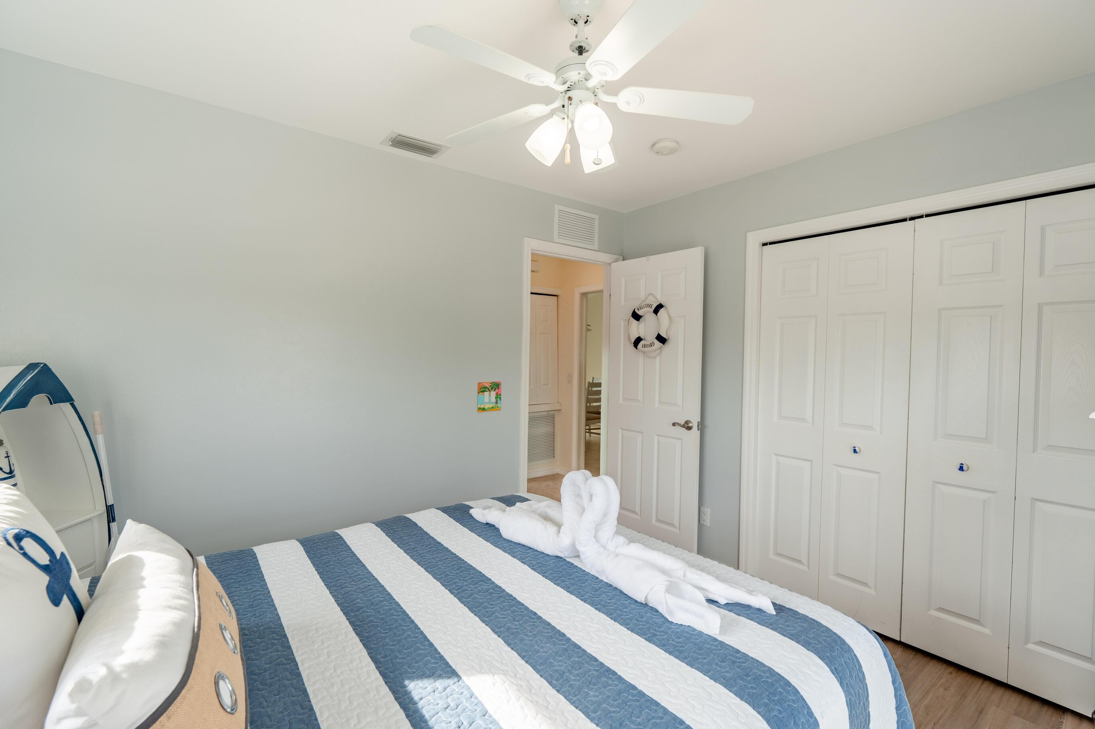 Une chambre à coucher avec un lit, un ventilateur de plafond et une armoire.