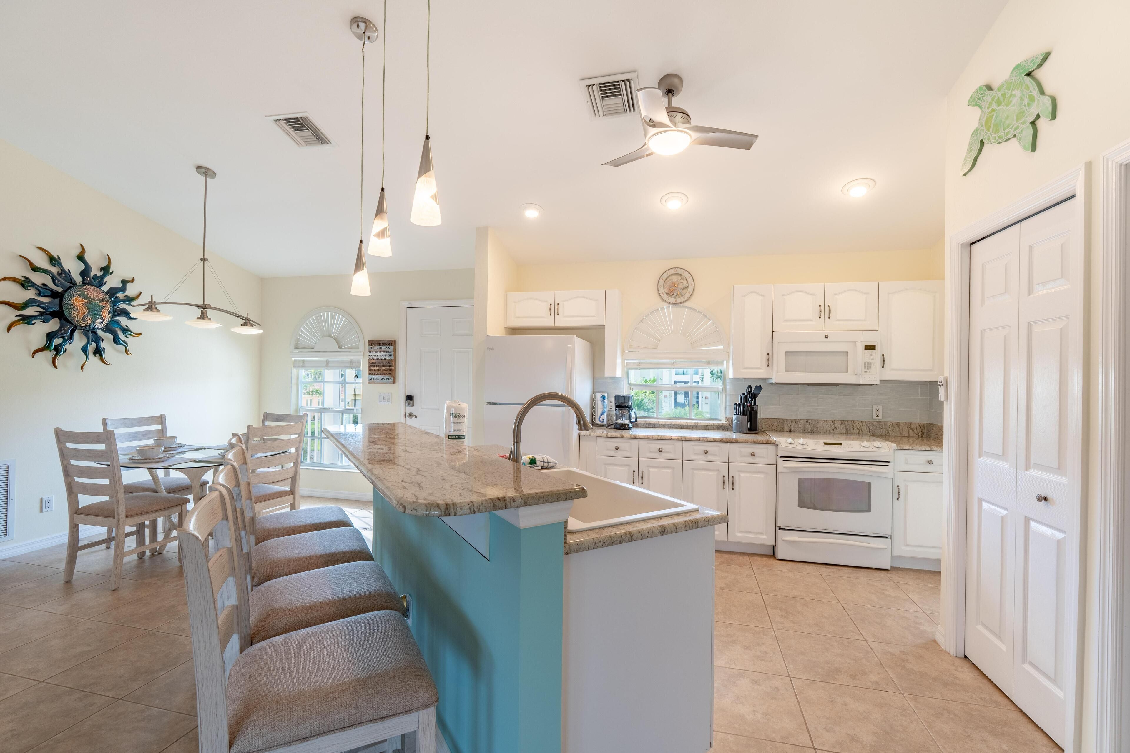 A modern kitchen with a central island, white cabinetry, a built-in oven, and a microwave.
