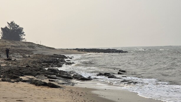 A beach with rocky terrain and a person standing near the water. - Sea view villa (Shrivardhan)