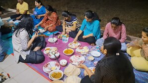 A group of people sitting on the ground around a table with food and drinks. - Sea view villa (Shrivardhan)