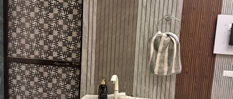 Un baño con lavamanos de mármol, una toalla colgada en un perchero y una puerta con diseño.