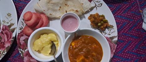 A plate with various dishes including flatbreads, a bowl of curry, a bowl of chutney, and a bowl of yogurt.