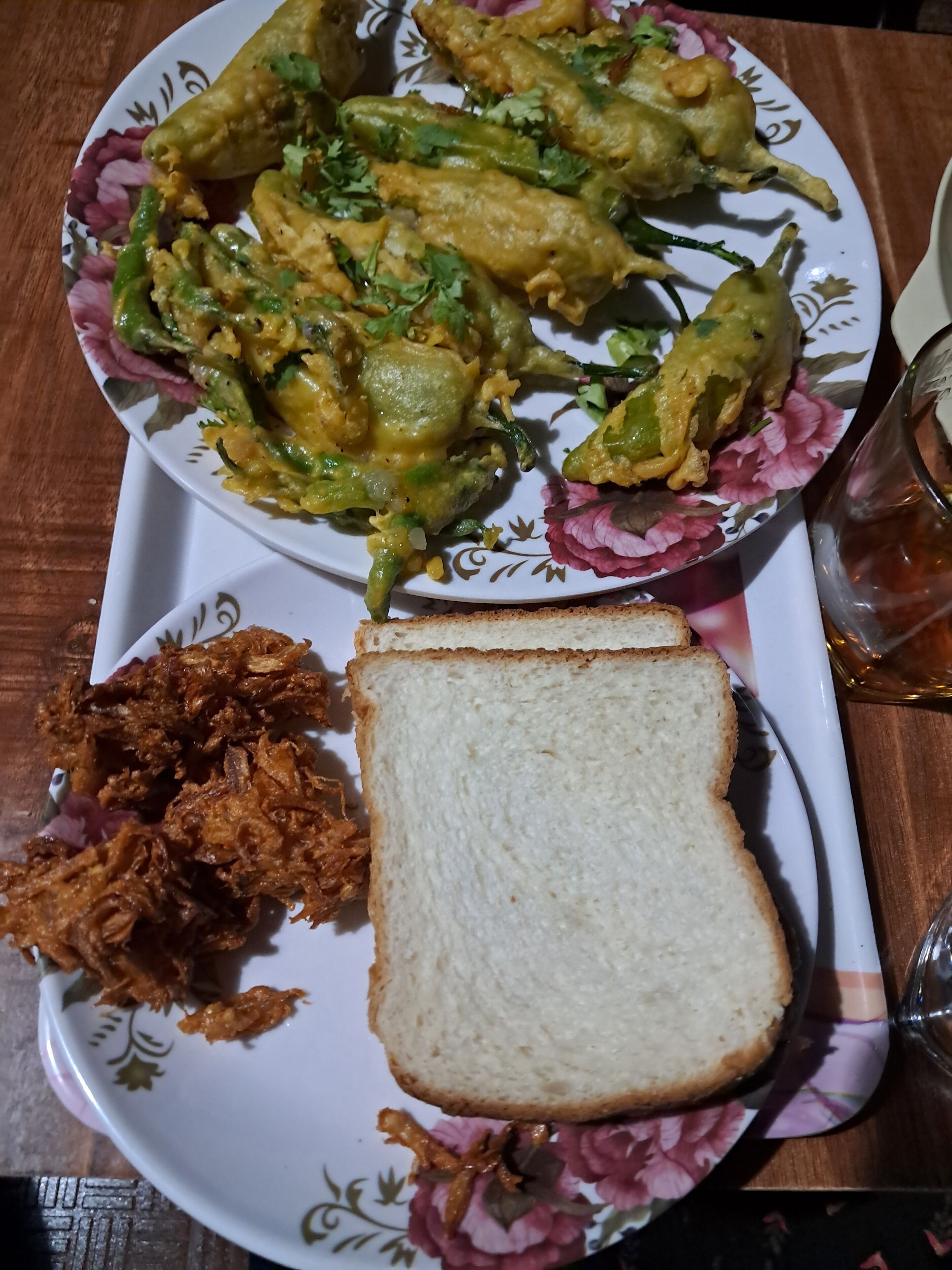A plate with fried vegetables, a slice of bread, and a glass of water on a table.