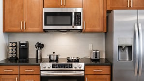 A kitchen with wooden cabinets, a stainless steel microwave, a refrigerator, a coffee maker, a toaster, and an oven. - Cozy Luxe Suite R&R HoF, Casino, Stadium, Airport (Cleveland)