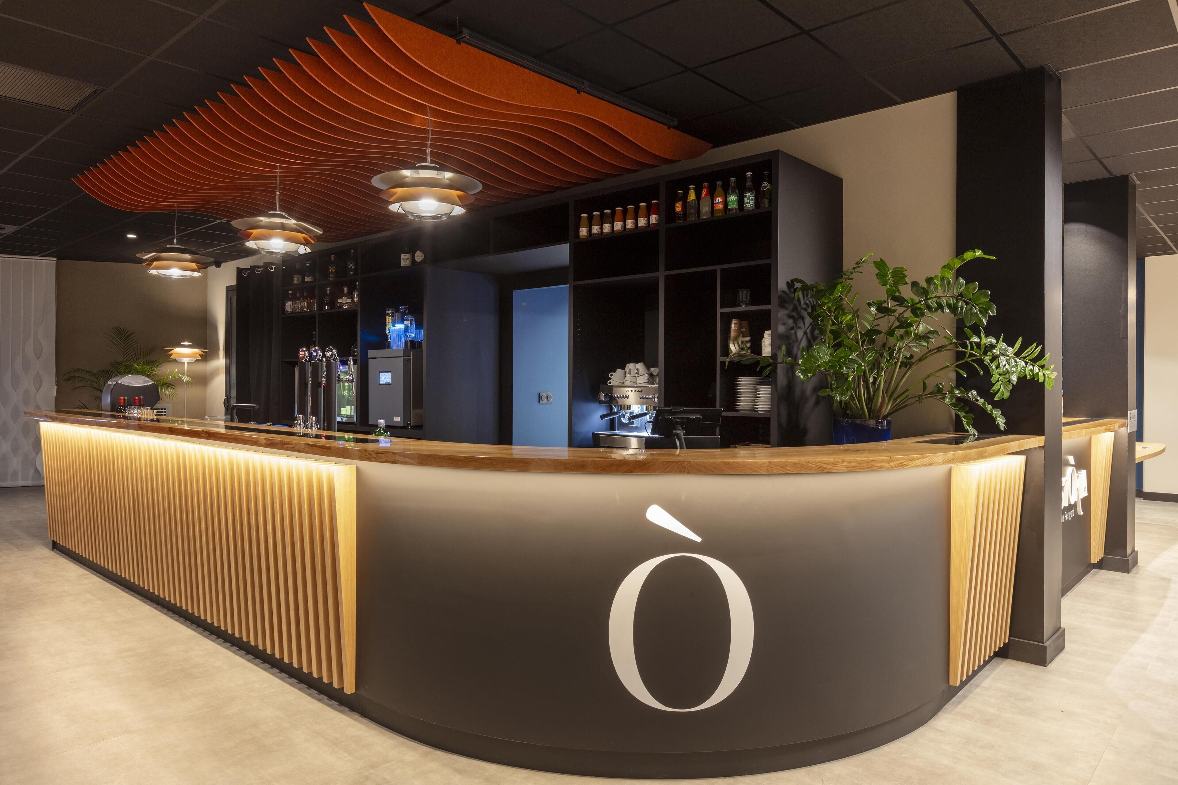 A modern reception area with a curved counter, a large 'O' logo, and a variety of bar equipment.