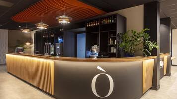 Un espace d’accueil moderne doté d’un comptoir incurvé, d’un grand logo en forme de « O » et de divers équipements de bar.
