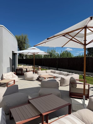 An outdoor patio with a sectional sofa, a wooden table, and two large umbrellas. - Hôtel Ostoria Périgueux, BW Signature Collection (Marsac-sur-l'Isle)