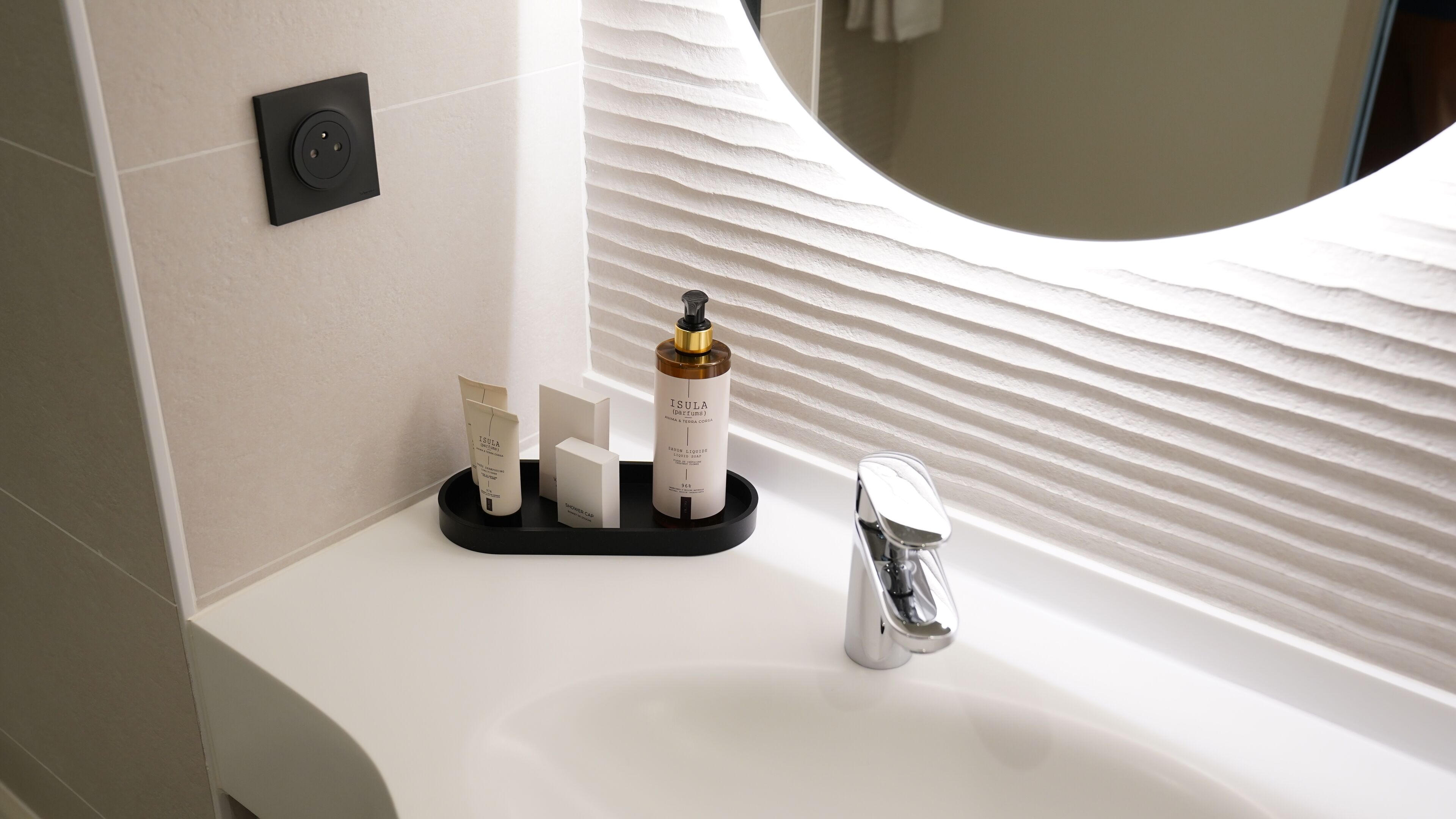 Un meuble-lavabo de salle de bain avec un lavabo blanc, un robinet moderne et un distributeur de savon.