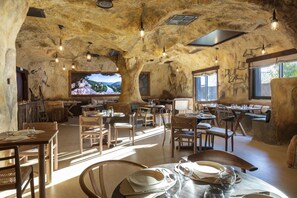 A rustic dining area with wooden furniture, stone walls, and hanging light fixtures. - Hôtel Ostoria Périgueux, BW Signature Collection (Marsac-sur-l'Isle)