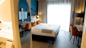 A hotel room with a bed, a desk, a chair, a mirror, and a window with curtains. - Hôtel Ostoria Périgueux, BW Signature Collection (Marsac-sur-l'Isle)