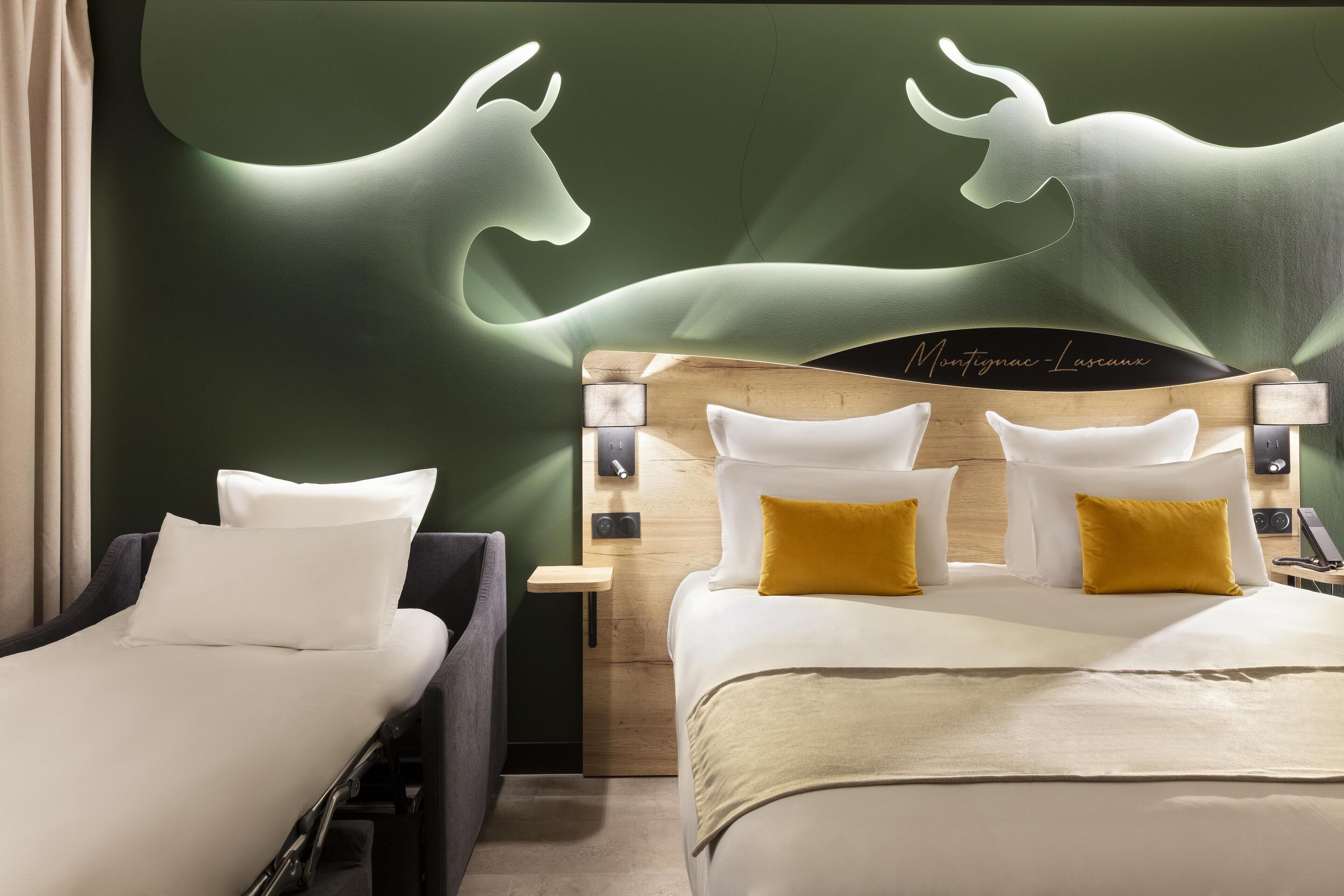 Une chambre d’hôtel avec deux lits, une tête de lit en bois et un mur vert orné de la silhouette d’un taureau.