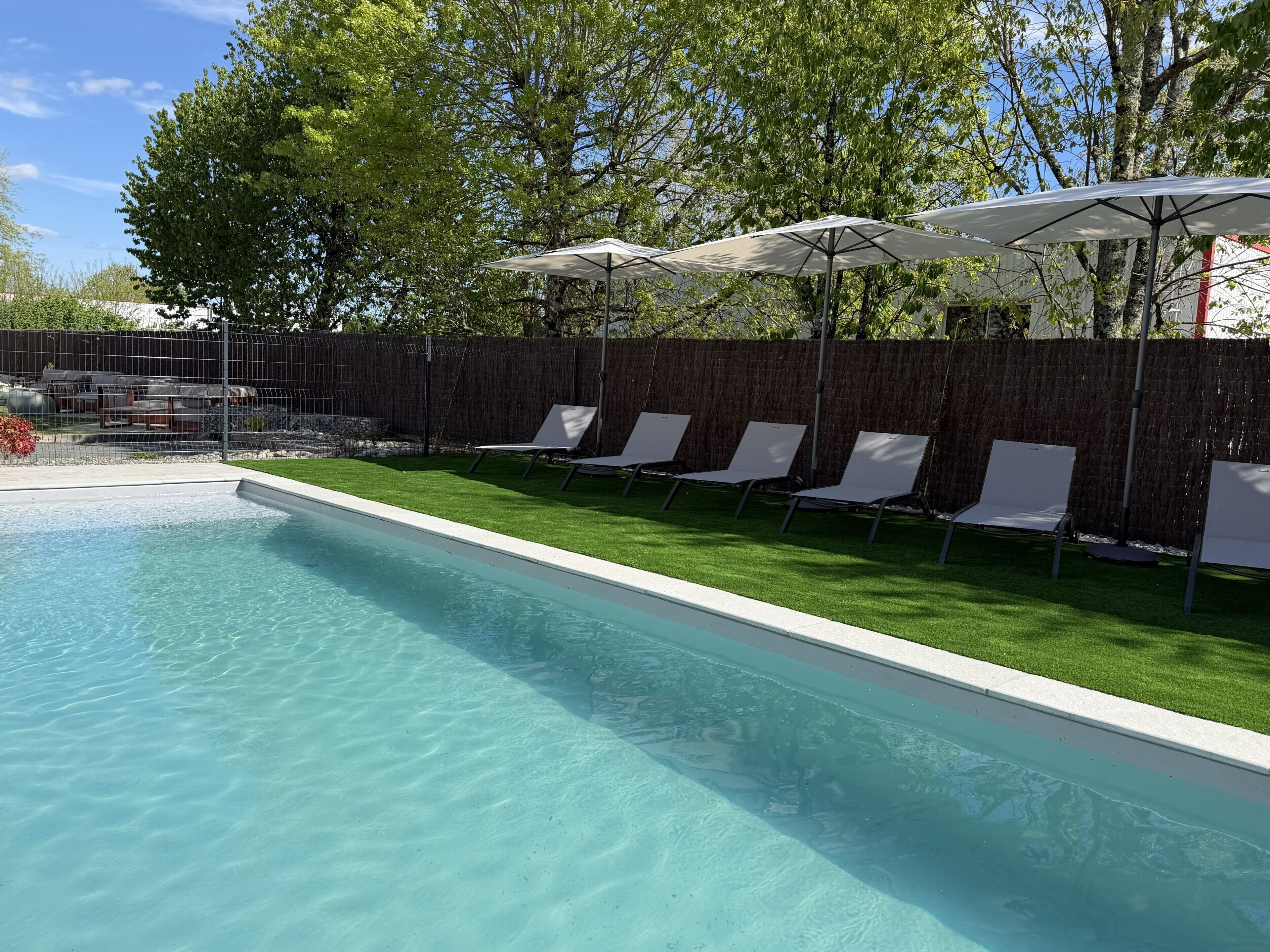 En säsongsöppen utomhuspool, parasoller och solstolar