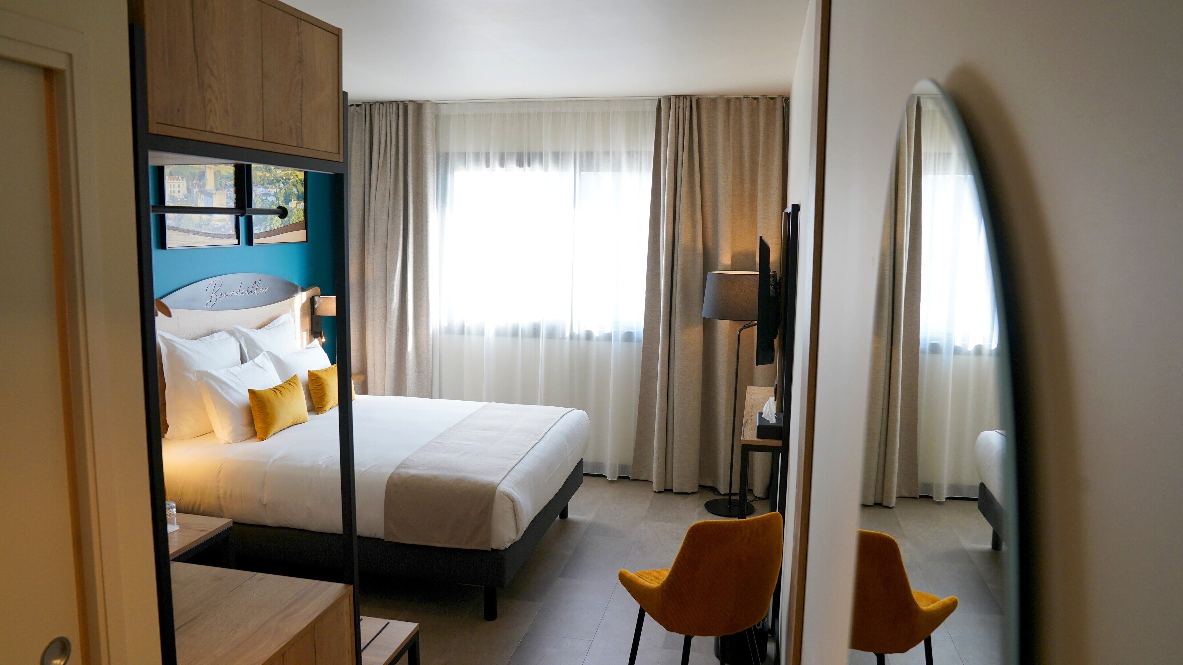 Una habitación de hotel con una cama, un escritorio, una silla y un televisor.
