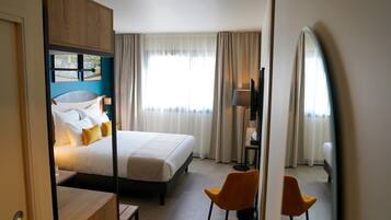 Una habitación de hotel con una cama, un escritorio, una silla y un televisor.