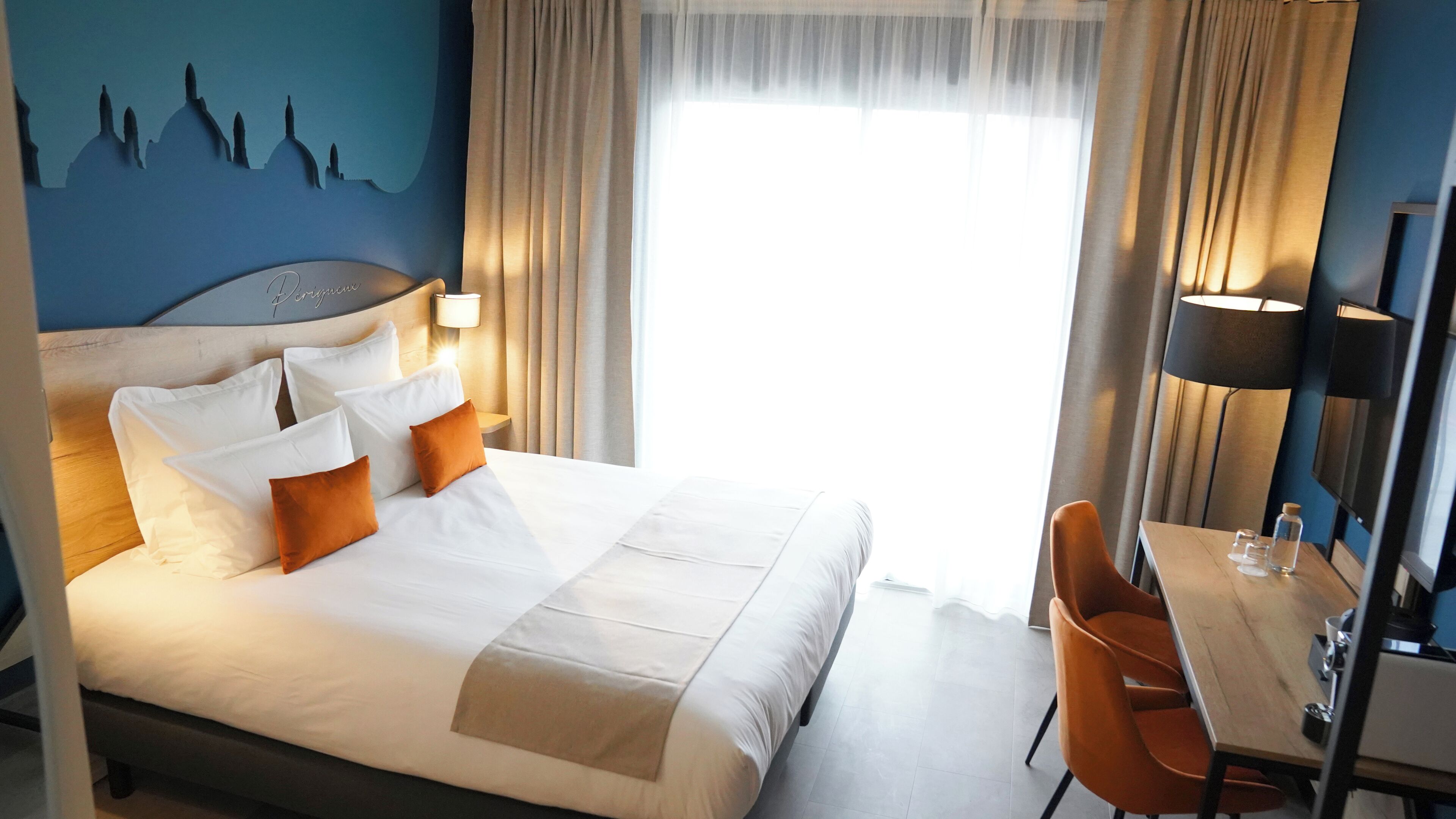 Una camera d'albergo con un letto, una scrivania e una sedia.