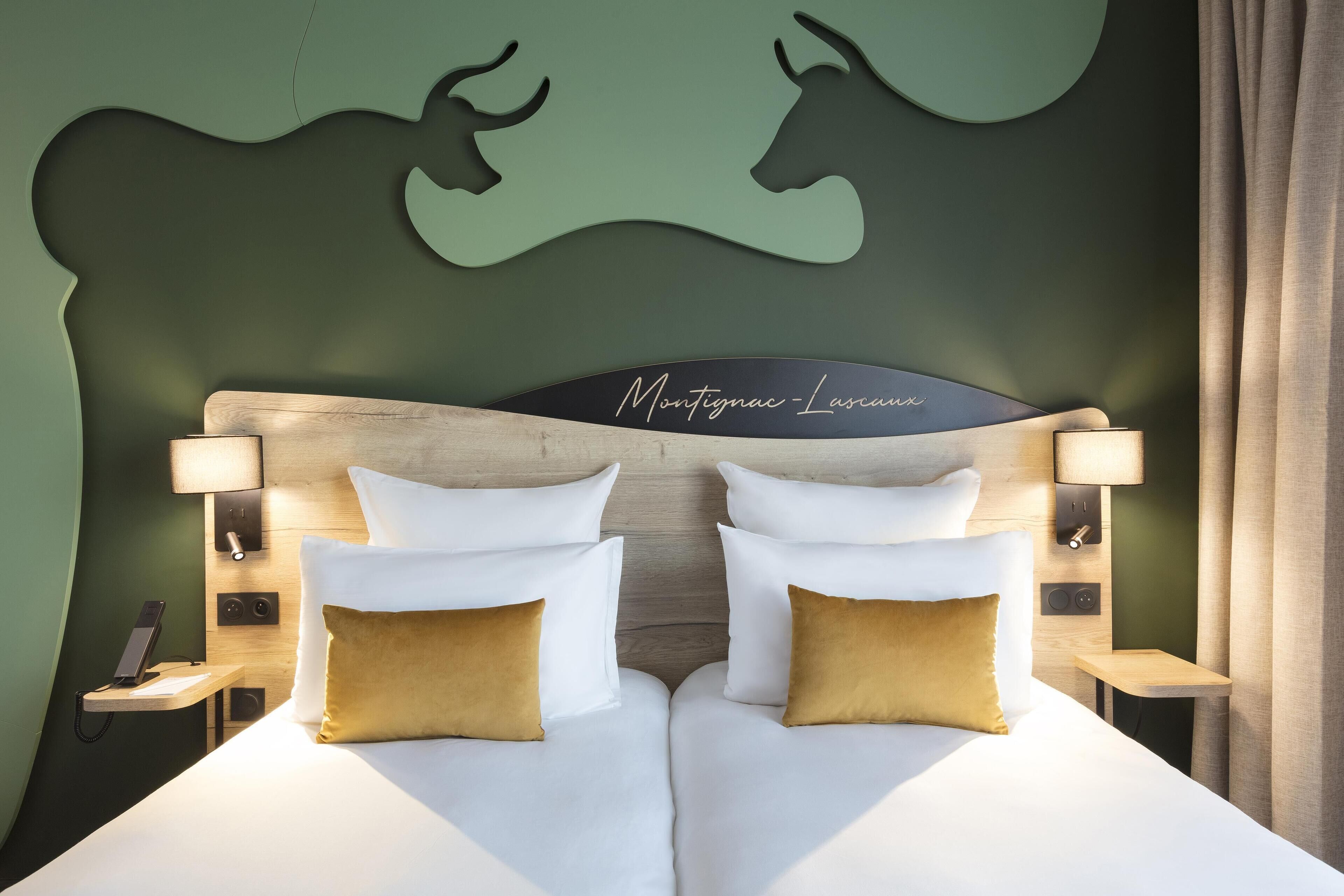 A double bed with white and gold pillows, a wooden headboard, and a wall-mounted artwork of two deer.