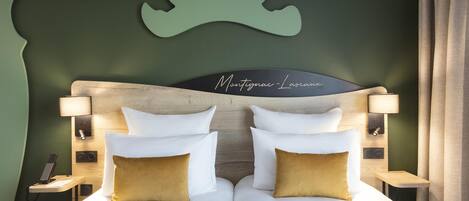 Una cama doble con almohadas blancas y doradas, un cabecero de madera y una obra de arte en la pared con dos ciervos.