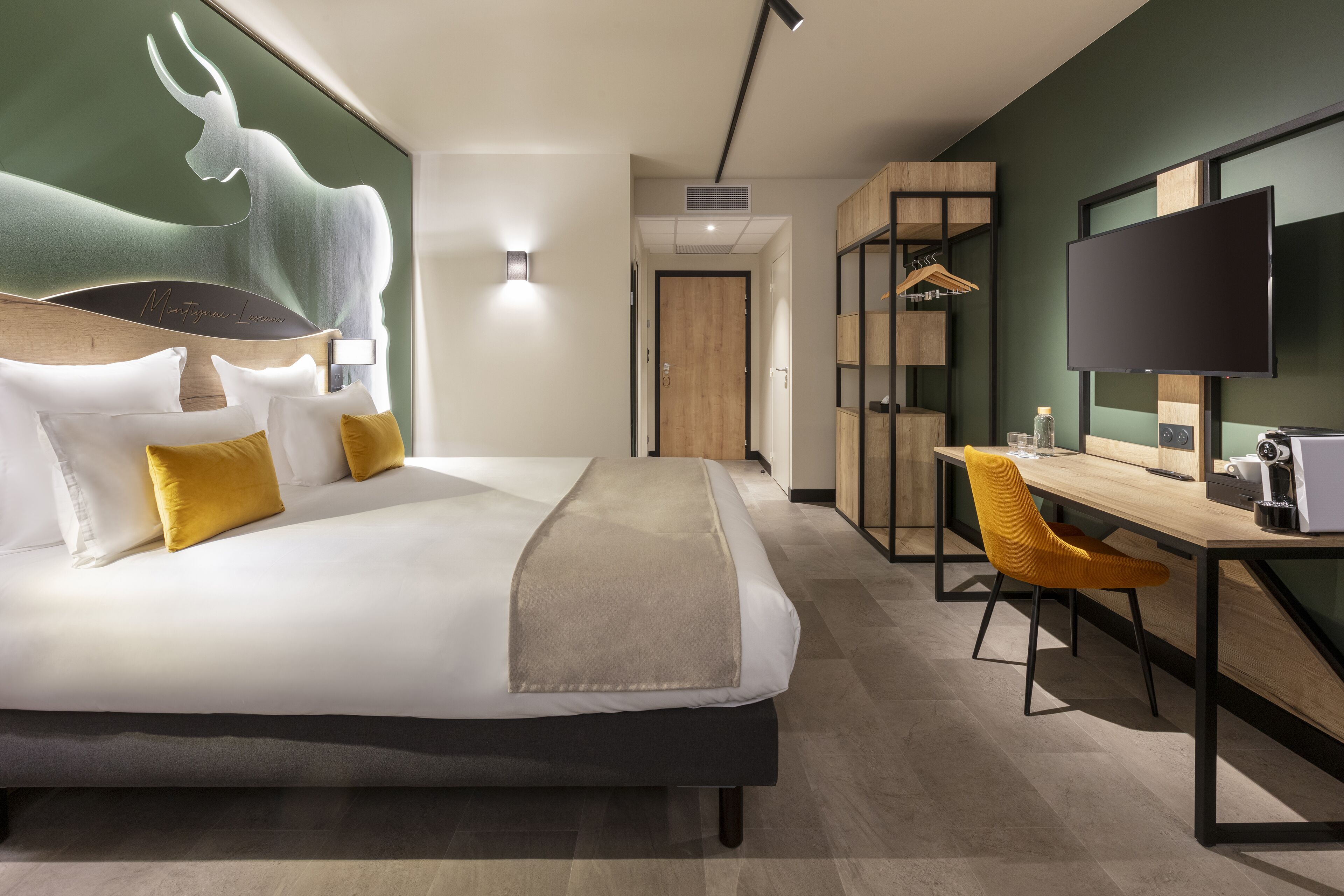 Et moderne hotelværelse med en stor seng, et skrivebord, en stol, et fjernsyn og et klædeskab.