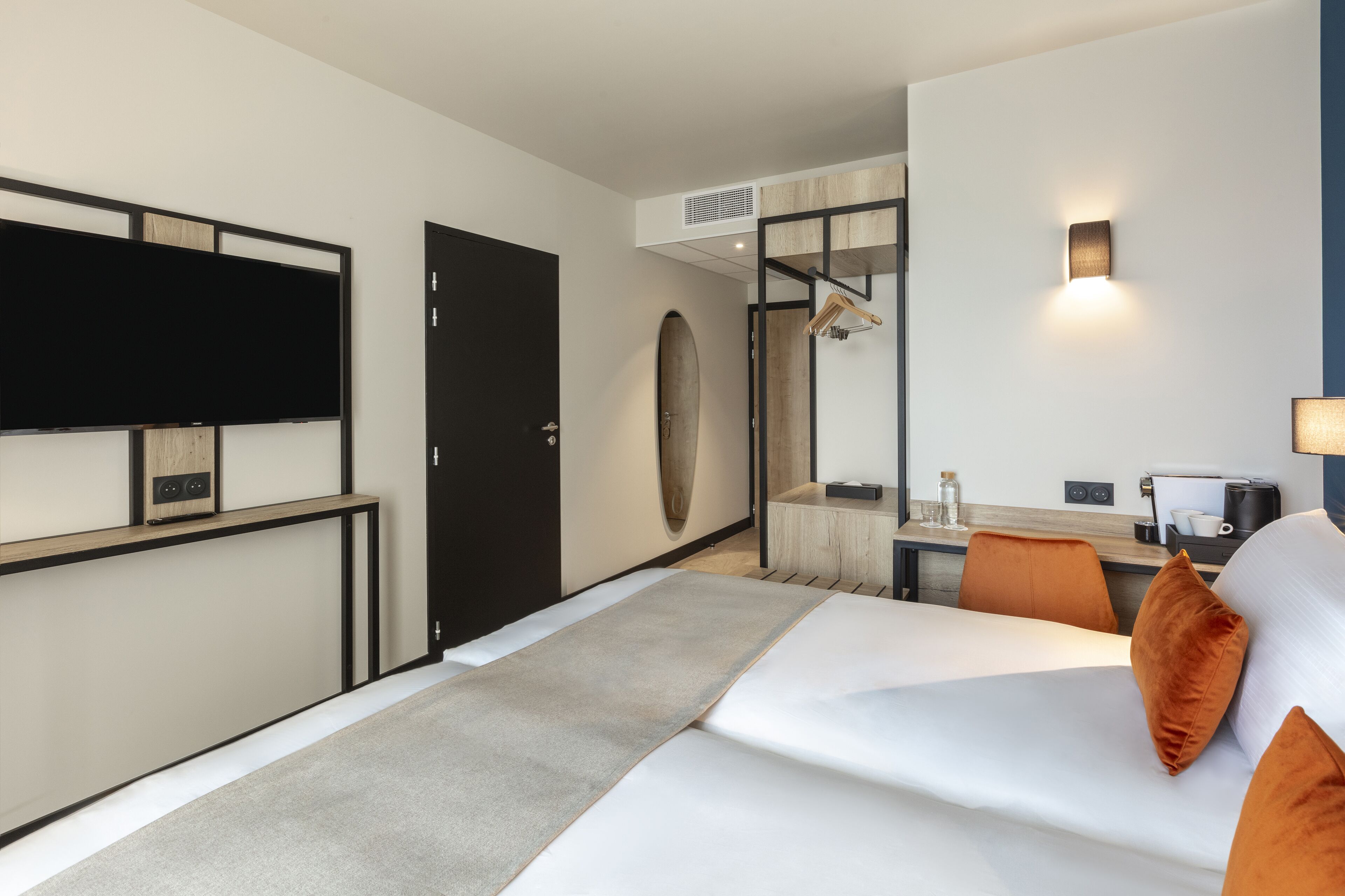 Une chambre d’hôtel avec un lit, un bureau, une chaise, une télévision et un miroir.