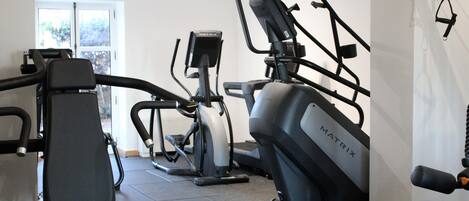 Een sportschool met diverse trainingsapparaten, waaronder loopbanden en elliptische trainers.
