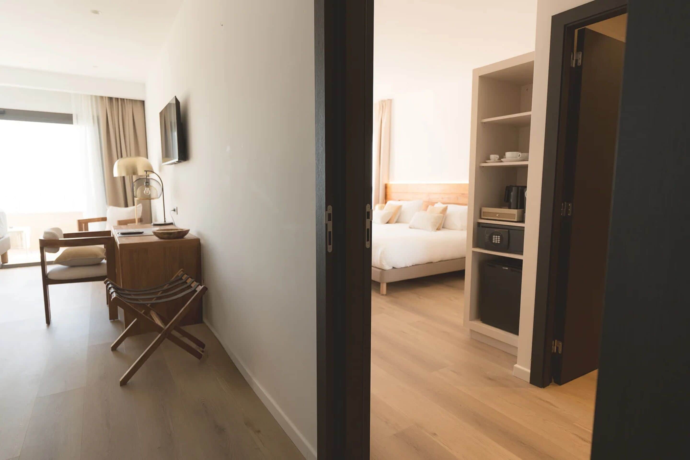 A hotel room with a bed, bedside tables, a chair, a desk, and a wardrobe.