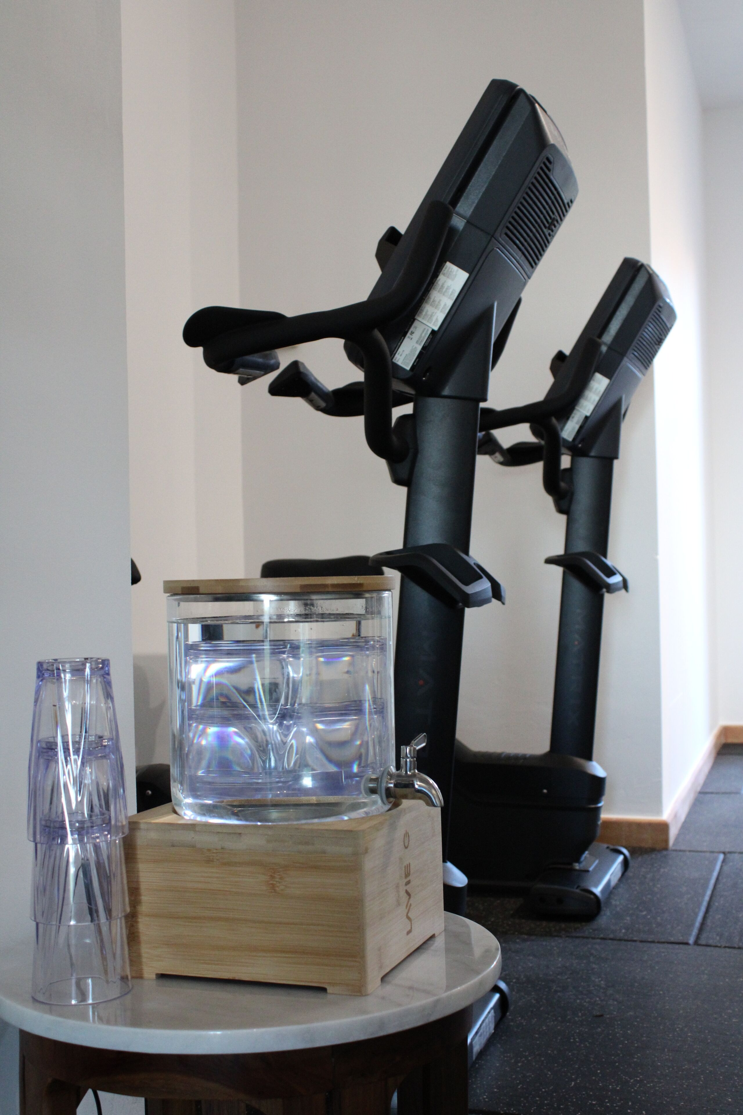 A room with exercise equipment, a glass container, and a wooden box on a table.