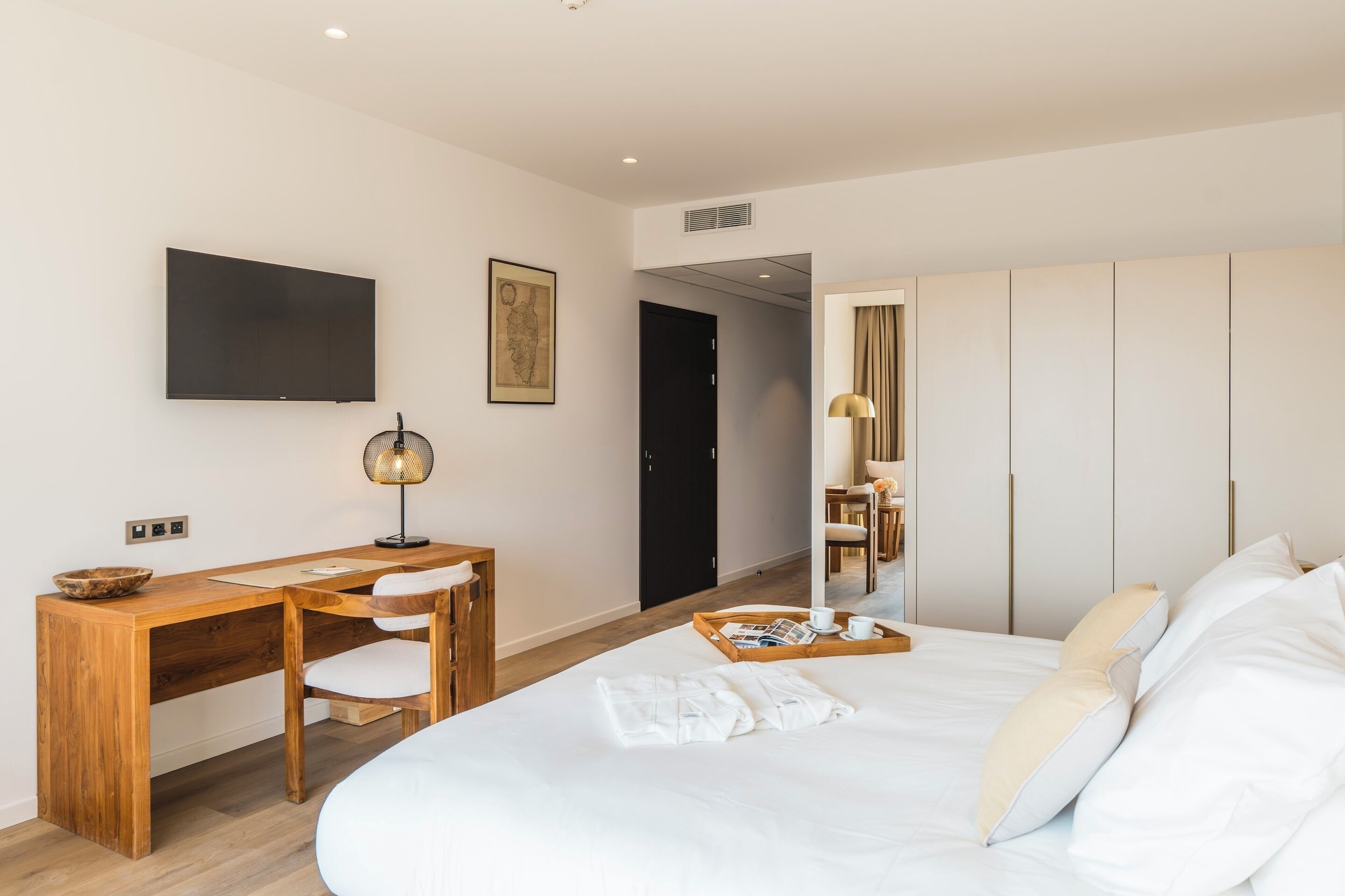 Una camera d'hotel moderna con un letto grande, una scrivania in legno, una TV a schermo piatto e un armadio.