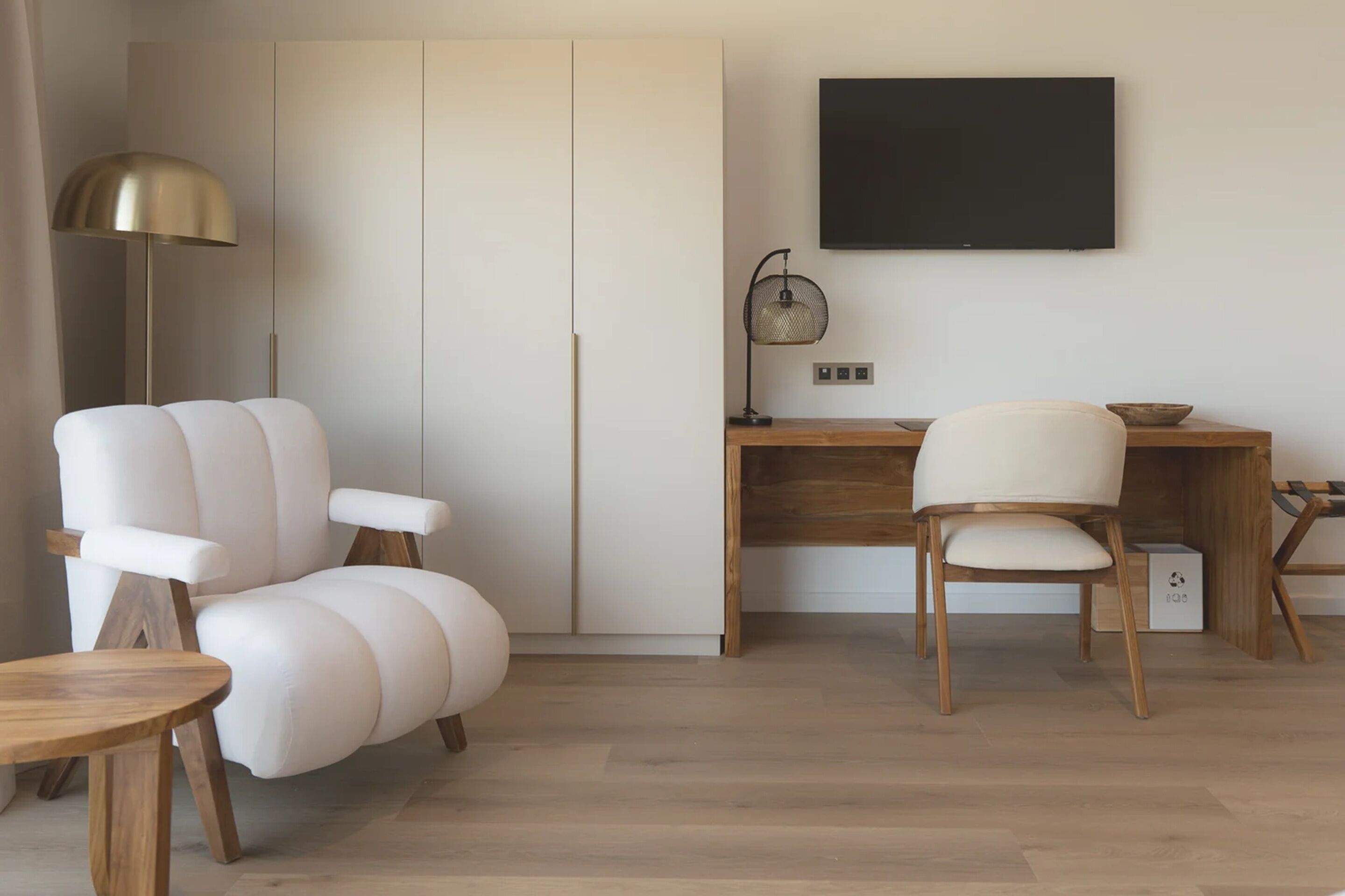 A modern living room with a sofa, two chairs, a desk, a television, and a floor lamp.