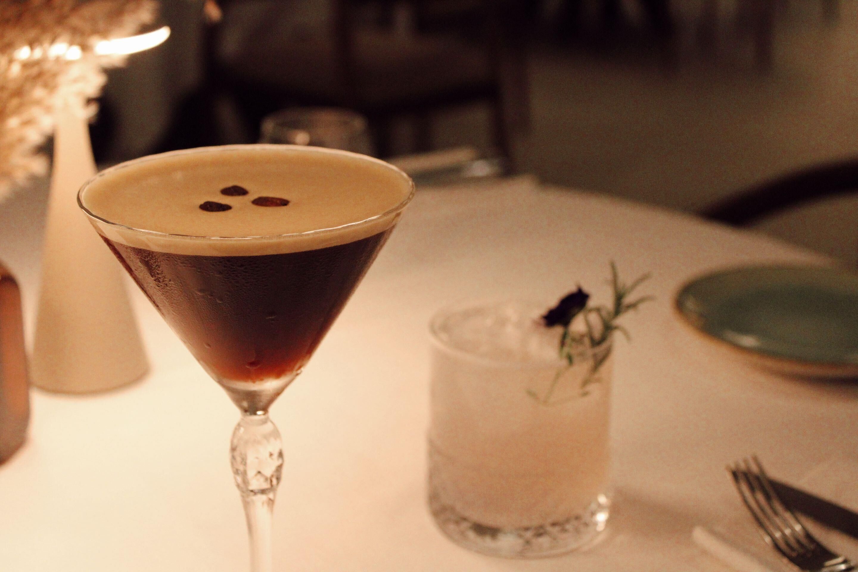 A martini glass with a frothy top on a table.