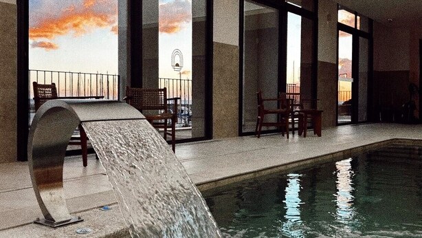 A pool area with a waterfall feature, large windows, and outdoor seating. - Best Western Premier A Storia Solenzara (Sari-Solenzara)