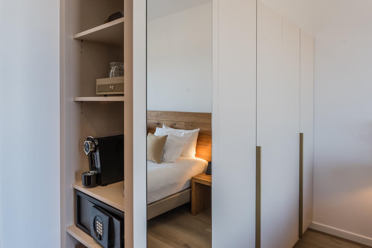 Une chambre à coucher comprenant un lit, une table de chevet et un coffre-fort encastré.