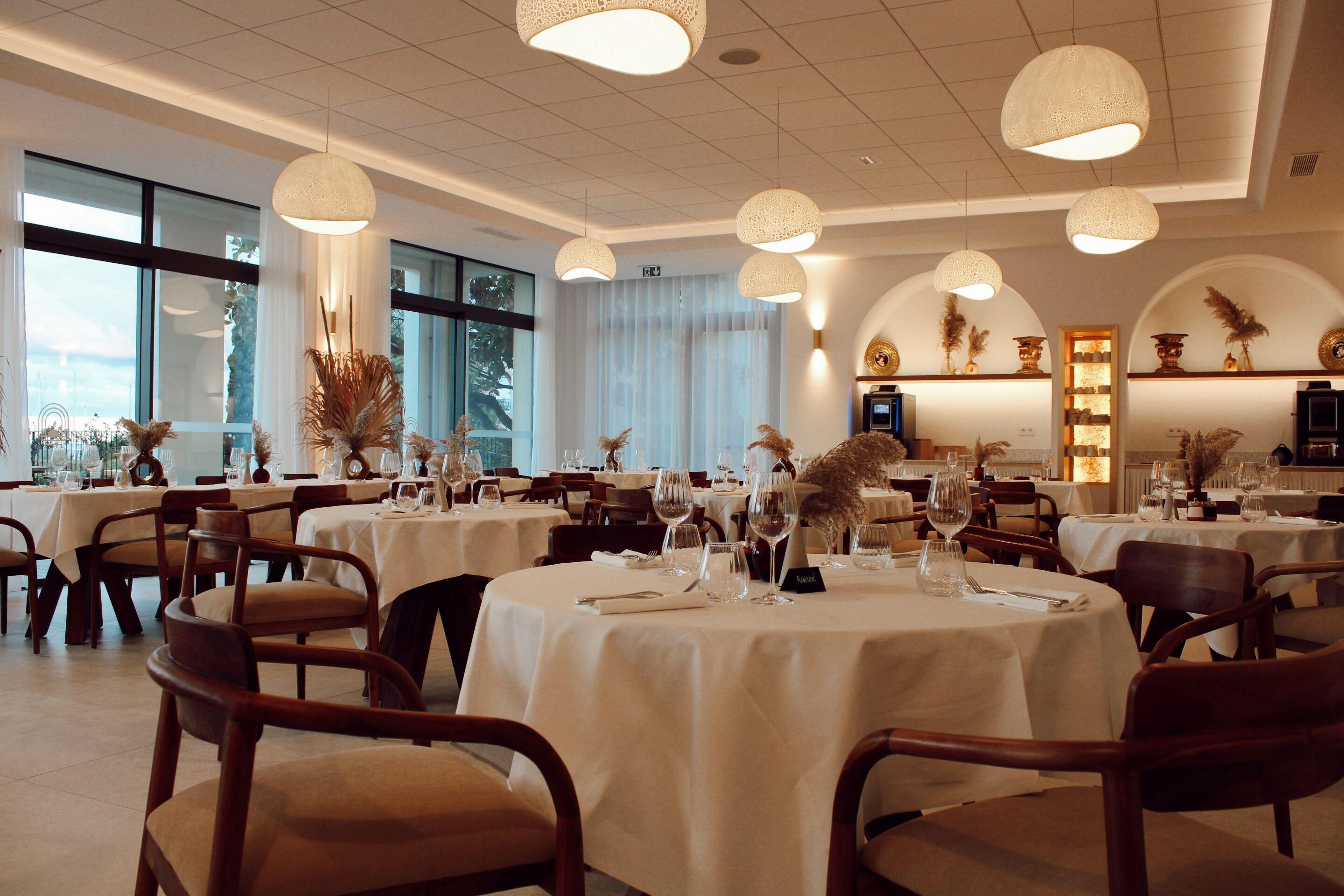 Ein Restaurant mit runden Tischen, Stühlen und hängenden Leuchten.