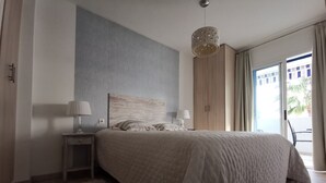 A modern bedroom with a large bed, a nightstand, a lamp, and a view of the outdoors. - Sunny Otylia apartment ☀️☀️☀️ with sea and garden views (Orihuela Costa)