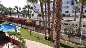 A pool area with palm trees and a view of a residential building. - Sunny Otylia apartment ☀️☀️☀️ with sea and garden views (Orihuela Costa)