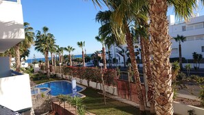 A pool area with palm trees, a clear sky, and a view of the sea. - Sunny Otylia apartment ☀️☀️☀️ with sea and garden views (Orihuela Costa)