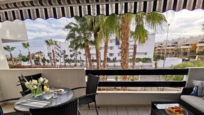 A balcony with a table and chairs, a sofa, and a bowl of fruit. - Sunny Otylia apartment ☀️☀️☀️ with sea and garden views (Orihuela Costa)