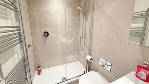 A modern bathroom with a glass-enclosed shower, a white sink, and a toilet.
