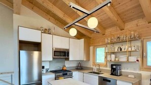 A modern kitchen with a central island, stainless steel appliances, and wooden beams on the ceiling. - Chalet Homestake View between Vail and Leadville (Red Cliff)