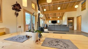A spacious living area with a wooden ceiling, a sofa, a TV, and a dining table with placemats. - Chalet Homestake View between Vail and Leadville (Red Cliff)
