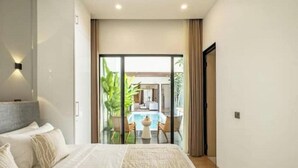 Habitación de hotel moderna con una cama grande, vista a una piscina y puerta de cristal que da a un balcón.