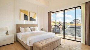 Una habitación de hotel moderna con una cama grande, una mesita de noche, un banco y vistas al exterior.