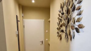A hallway with wooden flooring, a white door at the end, and a wall-mounted decorative piece. - Casa Mateo - Mediterranean vacation apartment in Bielefeld (Bielefeld)