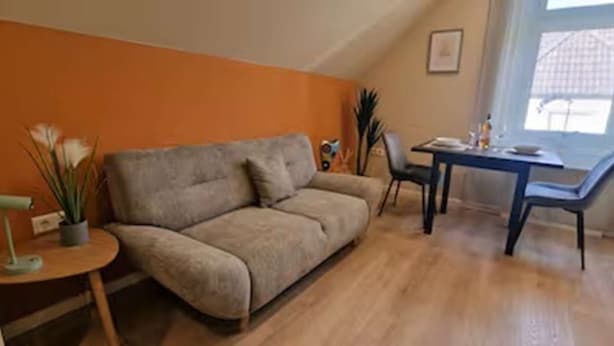 A living room with a sofa, a dining table, chairs, a small side table, and a potted plant. - Casa Mateo - Mediterranean vacation apartment in Bielefeld (Bielefeld)